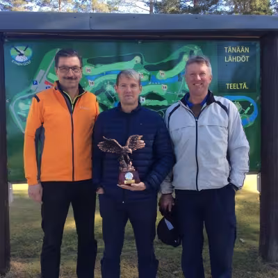 Muun Suomen joukkueen valitsija ja pelaaja Veijo Suomela (vas.) Kymen Golfin toimitusjohtaja Tommi Nousiainen ja kenttämestari Kimmo Korttila toivottavat kaikki tervetulleiksi Kotkaan. Kuvaan on päässyt myös komea Ryder Cupin kiertopalkinto.